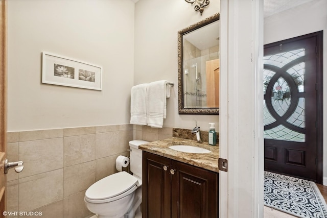 bathroom featuring vanity, toilet, and tile walls