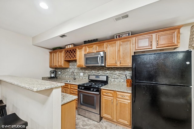 kitchen featuring a breakfast bar, backsplash, sink, appliances with stainless steel finishes, and light stone counters