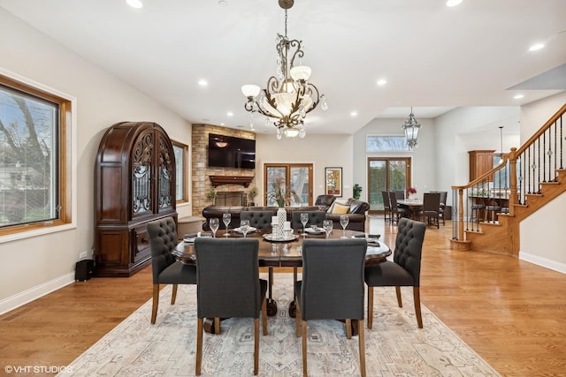 dining area with a stone fireplace, french doors, and light hardwood / wood-style floors