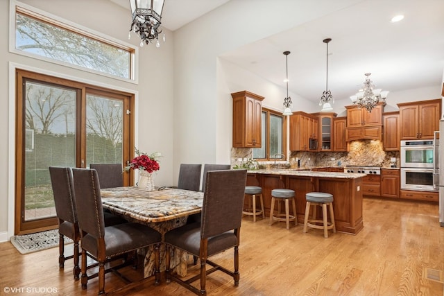 dining room with light hardwood / wood-style floors, an inviting chandelier, and a healthy amount of sunlight