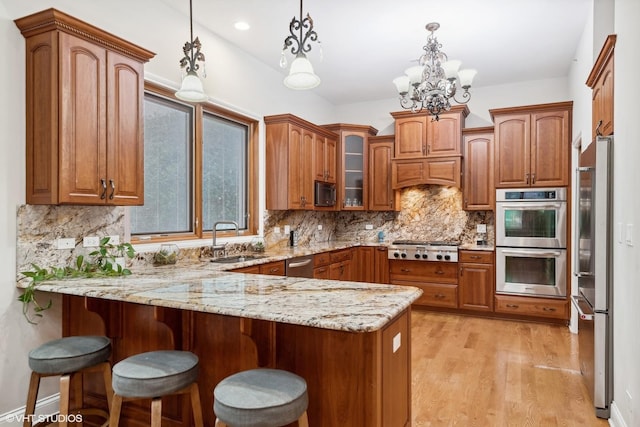 kitchen with backsplash, kitchen peninsula, pendant lighting, and appliances with stainless steel finishes