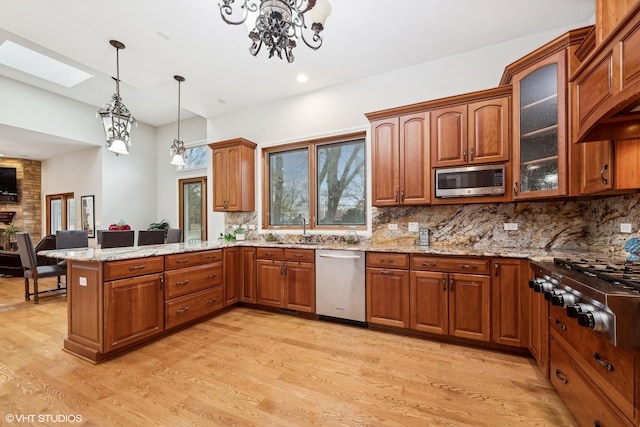 kitchen featuring decorative backsplash, stainless steel appliances, light stone counters, and a skylight