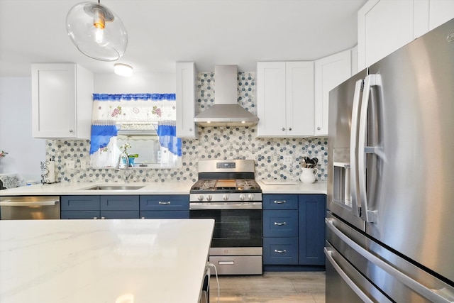 kitchen with wall chimney range hood, white cabinetry, sink, light hardwood / wood-style floors, and stainless steel appliances