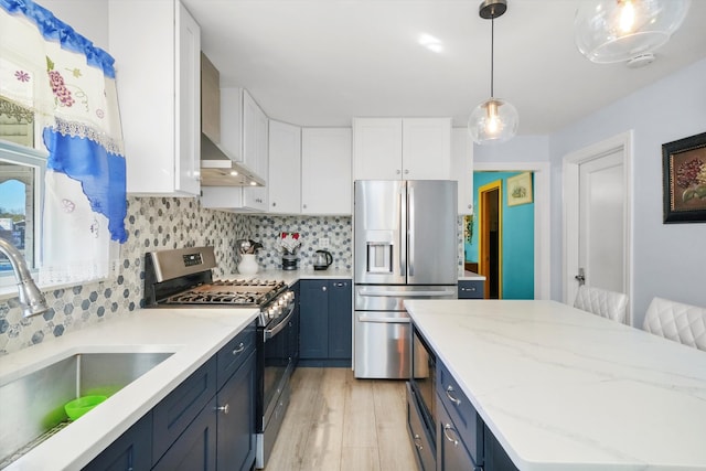 kitchen with appliances with stainless steel finishes, white cabinetry, blue cabinetry, sink, and decorative light fixtures