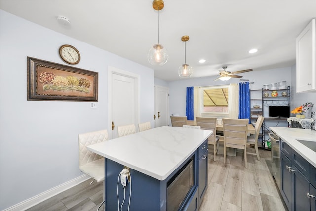 kitchen featuring a center island, hanging light fixtures, ceiling fan, light hardwood / wood-style floors, and white cabinets