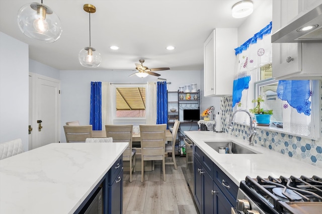 kitchen with white cabinetry, light wood-type flooring, blue cabinetry, sink, and decorative light fixtures