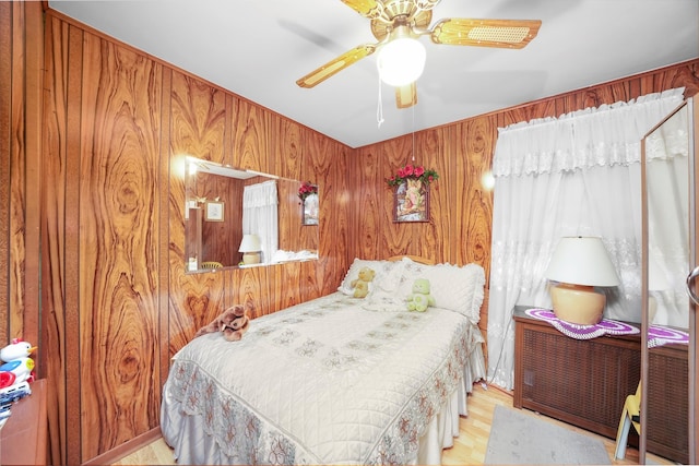 bedroom featuring light hardwood / wood-style flooring, radiator heating unit, wooden walls, and ceiling fan