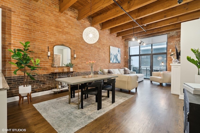 dining room featuring beam ceiling, a towering ceiling, dark wood-type flooring, brick wall, and wooden ceiling