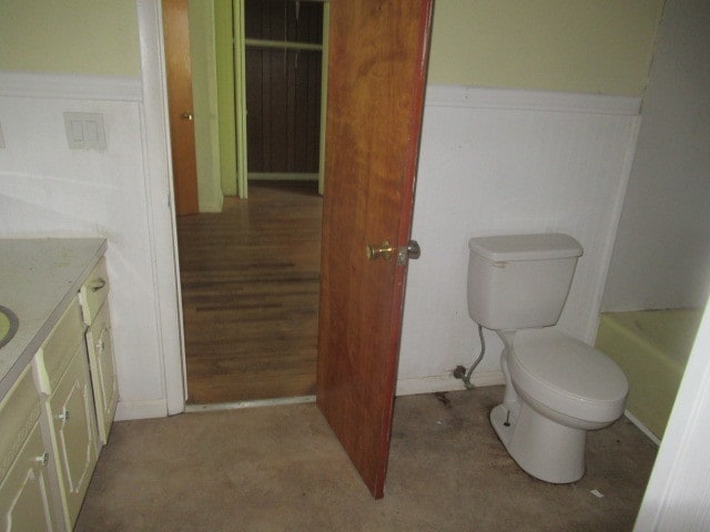 bathroom with a tub to relax in, toilet, and vanity