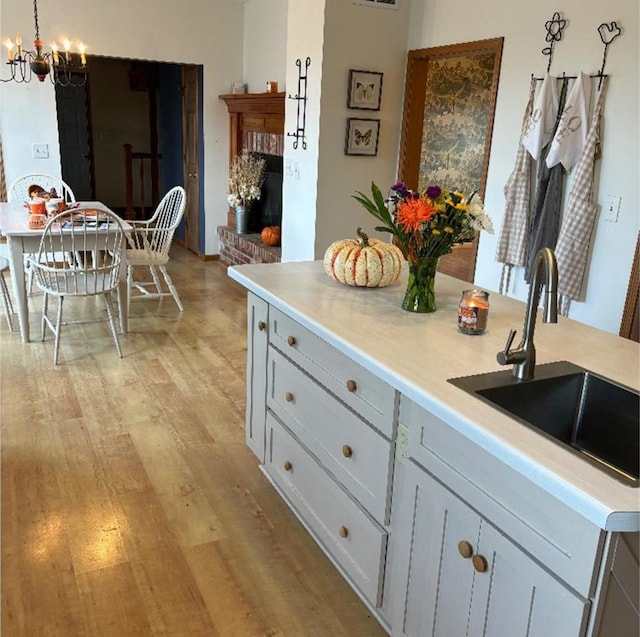 kitchen featuring sink, hanging light fixtures, a chandelier, light hardwood / wood-style flooring, and gray cabinetry