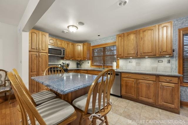 kitchen featuring stone counters, a kitchen island, plenty of natural light, and appliances with stainless steel finishes