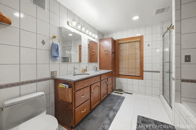 bathroom with vanity, tile patterned floors, toilet, tile walls, and walk in shower