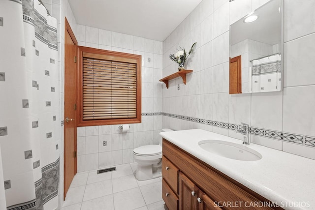 bathroom with vanity, tile patterned floors, gas water heater, toilet, and tile walls