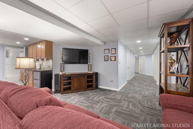 living room with a drop ceiling and dark colored carpet