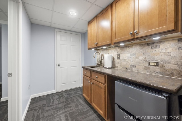 kitchen featuring a paneled ceiling, decorative backsplash, sink, and dark carpet