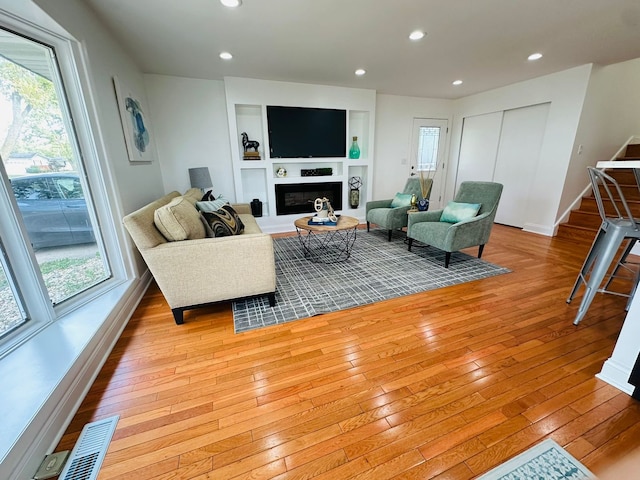 living room featuring built in shelves and light wood-type flooring