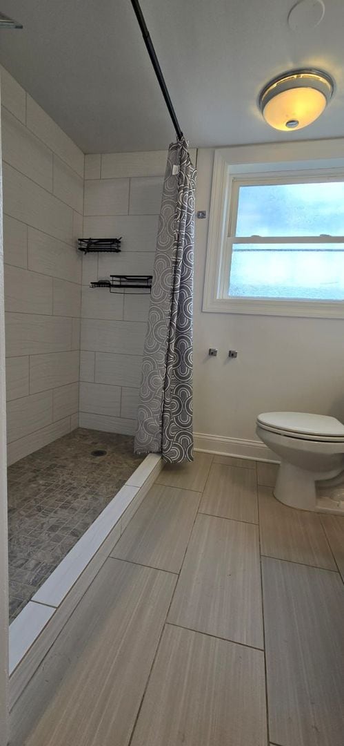 bathroom featuring toilet and curtained shower