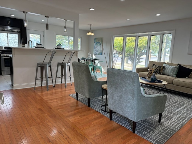 living room with plenty of natural light, a chandelier, and light hardwood / wood-style floors