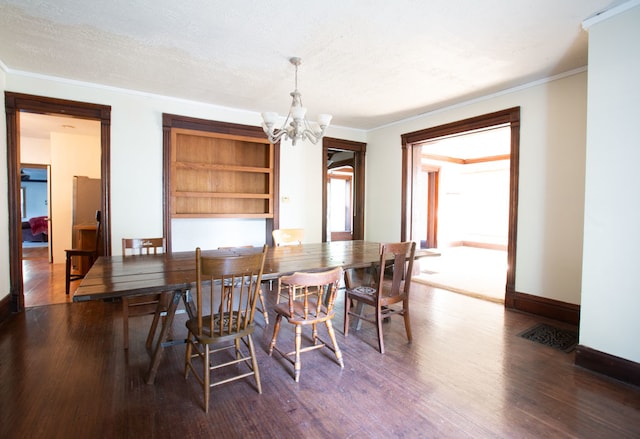 dining room with dark hardwood / wood-style floors, crown molding, a notable chandelier, and a textured ceiling