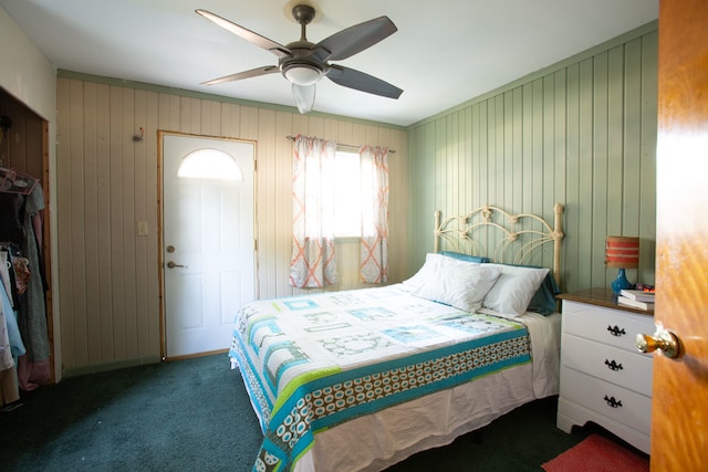 carpeted bedroom featuring wooden walls, ceiling fan, and a closet