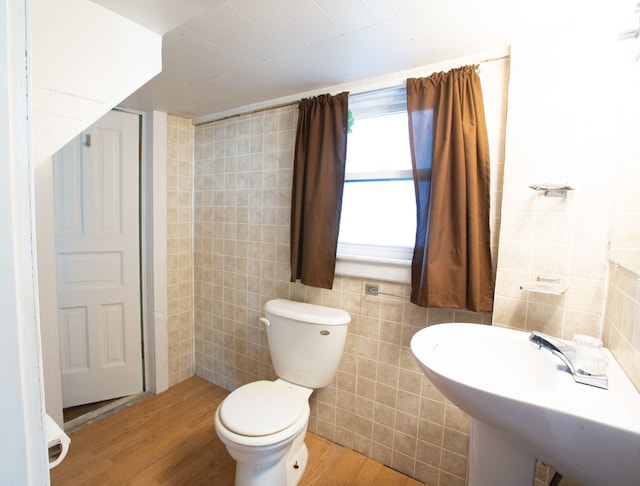 bathroom featuring wood-type flooring, sink, toilet, and tile walls