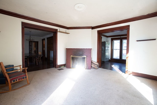 carpeted living room featuring a notable chandelier, a brick fireplace, and crown molding