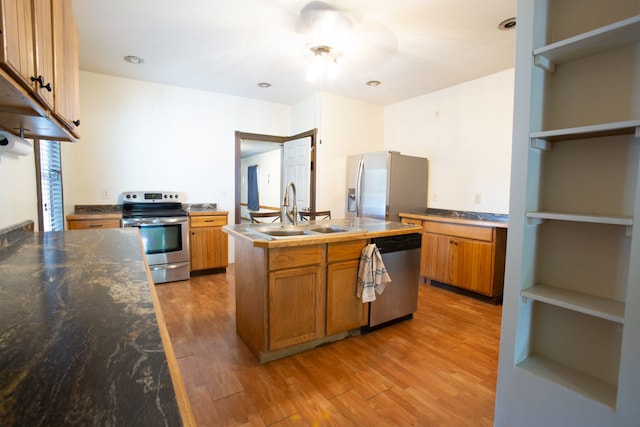 kitchen with appliances with stainless steel finishes, a center island, sink, and light hardwood / wood-style flooring