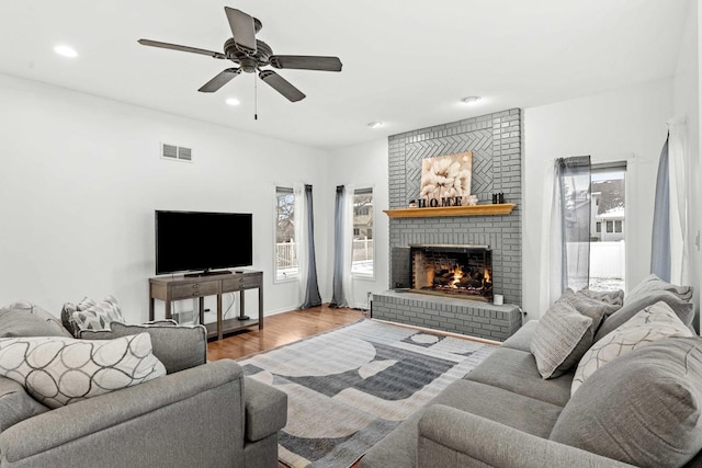 living room featuring ceiling fan, a fireplace, and hardwood / wood-style floors