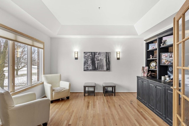 sitting room with light wood-type flooring and a tray ceiling