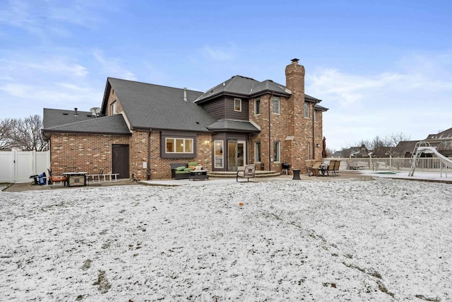 snow covered rear of property featuring a patio area and a swimming pool