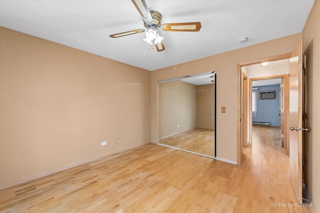 unfurnished bedroom featuring a wall unit AC, ceiling fan, a closet, and light hardwood / wood-style floors