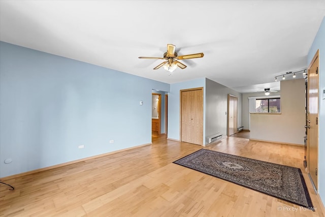 empty room featuring rail lighting, baseboard heating, and light hardwood / wood-style flooring