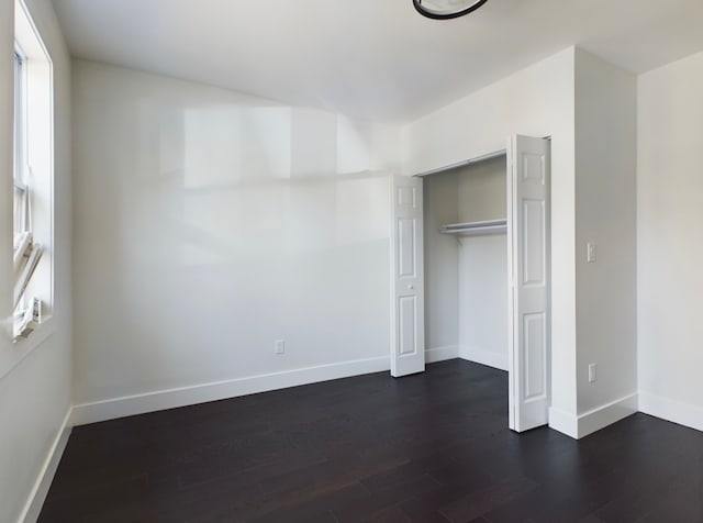 unfurnished bedroom featuring a closet and dark hardwood / wood-style flooring