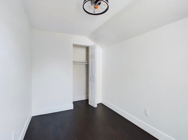 unfurnished bedroom with a closet, lofted ceiling, and dark hardwood / wood-style flooring