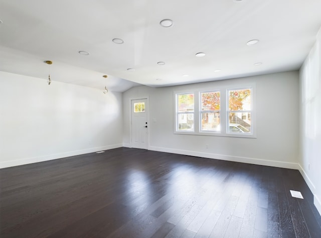 spare room featuring dark wood-type flooring and vaulted ceiling