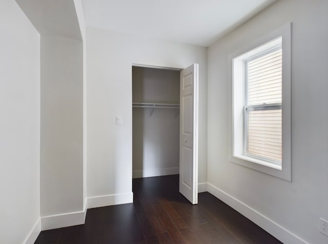 unfurnished bedroom with a closet and dark hardwood / wood-style flooring