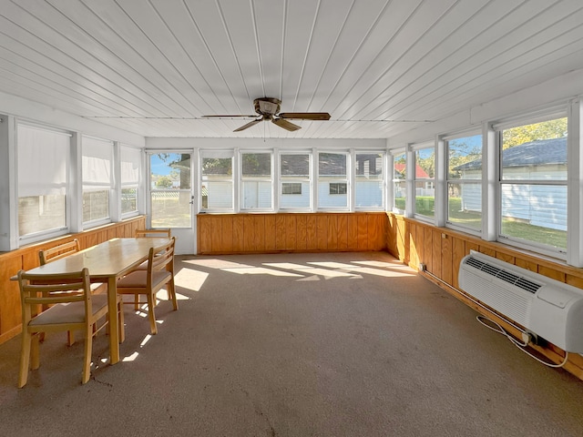 unfurnished sunroom with a wall mounted AC, ceiling fan, and plenty of natural light