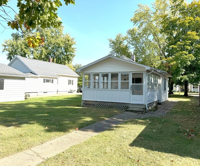 back of property featuring a sunroom, entry steps, a yard, and a chimney