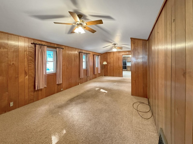 unfurnished living room featuring ceiling fan, carpet flooring, and wood walls