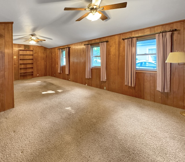 unfurnished room with wood walls, carpet, and ceiling fan