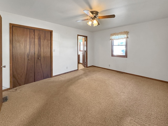 unfurnished bedroom with light colored carpet, a closet, and ceiling fan