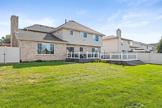 rear view of property featuring a wooden deck and a lawn