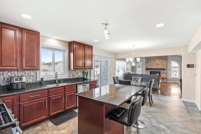 kitchen with pendant lighting, sink, a kitchen island, a fireplace, and decorative backsplash