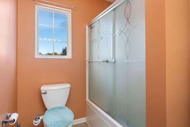 bathroom featuring bath / shower combo with glass door and toilet