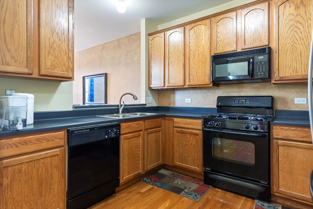 kitchen with light hardwood / wood-style floors, black appliances, and sink