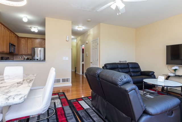 living room with ceiling fan, sink, and hardwood / wood-style floors