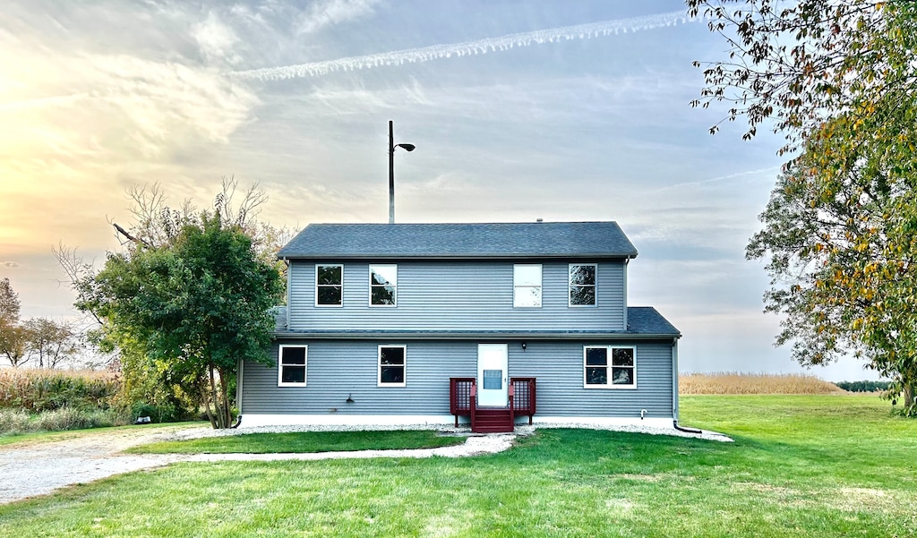 back house at dusk featuring a yard