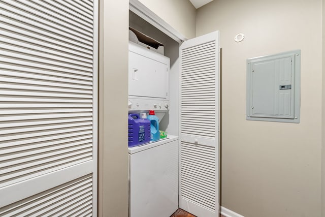 clothes washing area featuring electric panel and stacked washer / drying machine