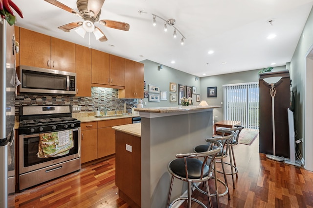 kitchen featuring dark wood-type flooring, appliances with stainless steel finishes, a kitchen island, and a kitchen breakfast bar