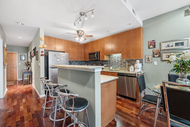 kitchen featuring appliances with stainless steel finishes, dark wood-type flooring, and a breakfast bar area